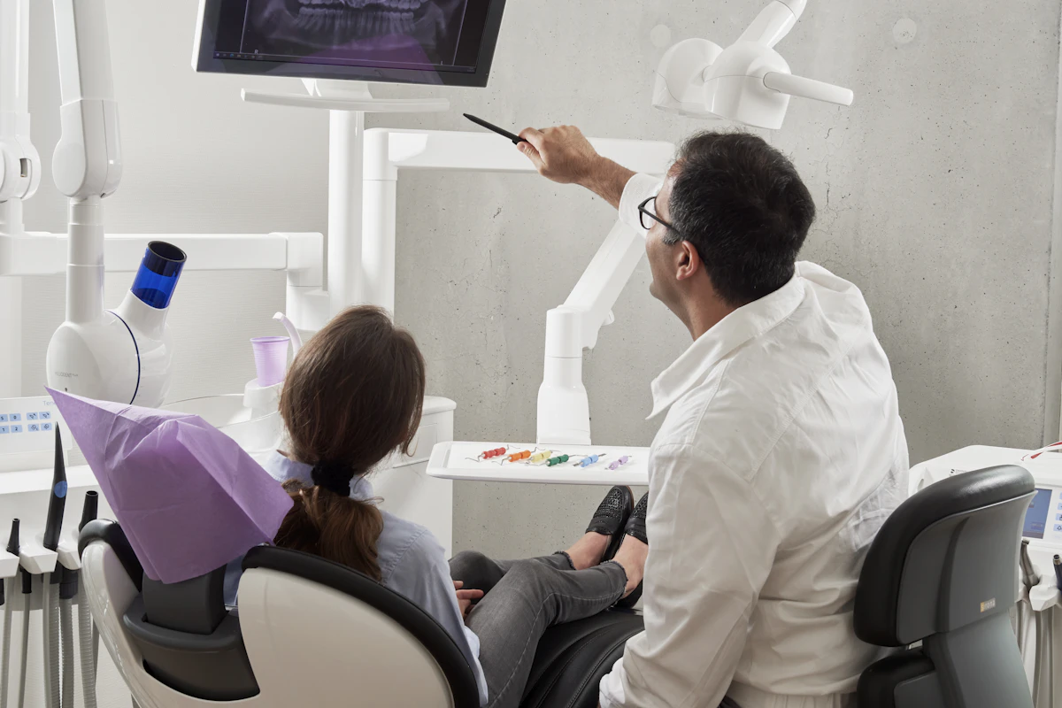 Orthodontist explaining dental panoramic X-rays and jaw structure to an adult patient during consultation
